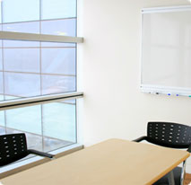 two chairs around a small desk with a whiteboard in the background