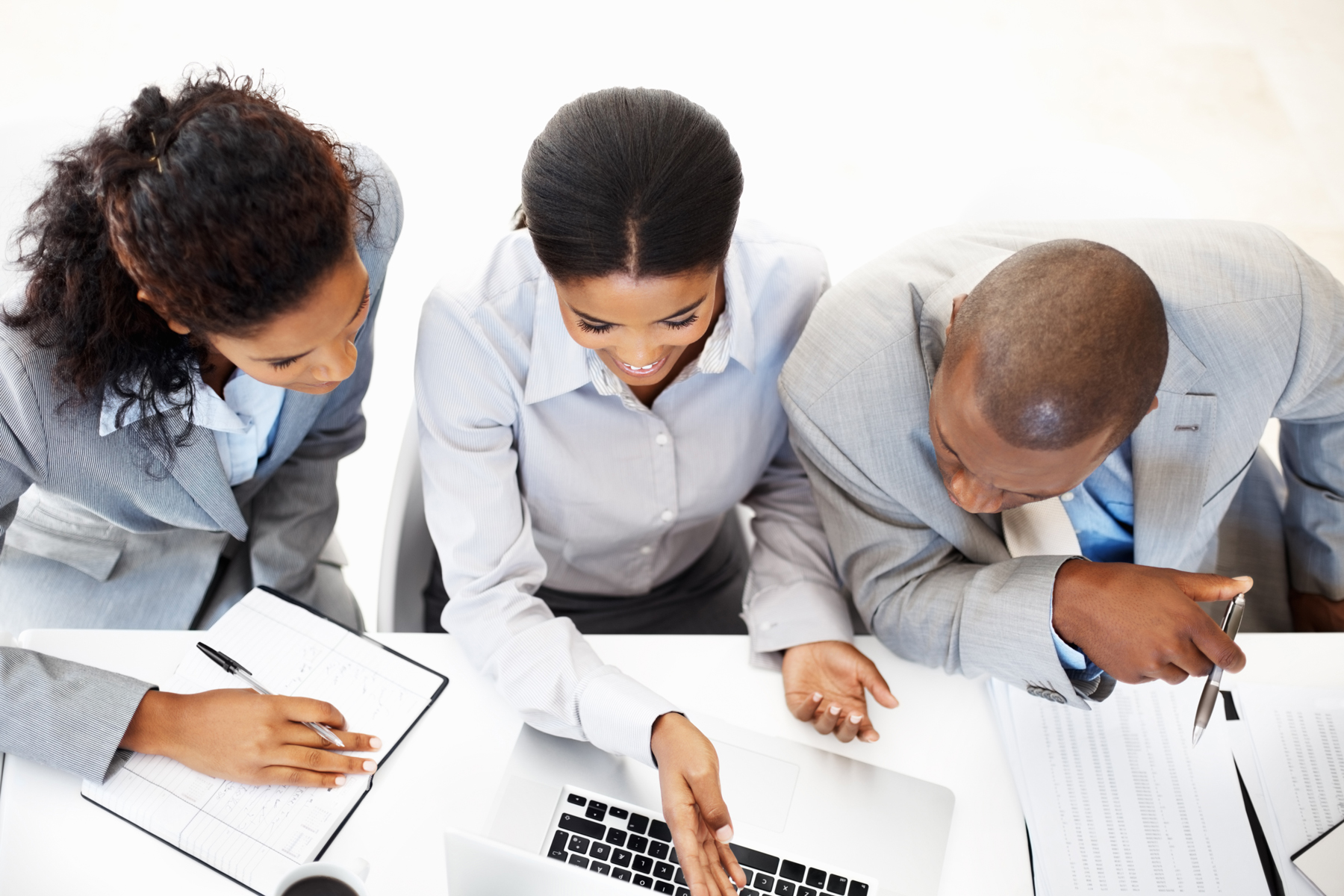 2 women IT Consultants with 1 male IT consultant working at a desk with a laptop and paperwork