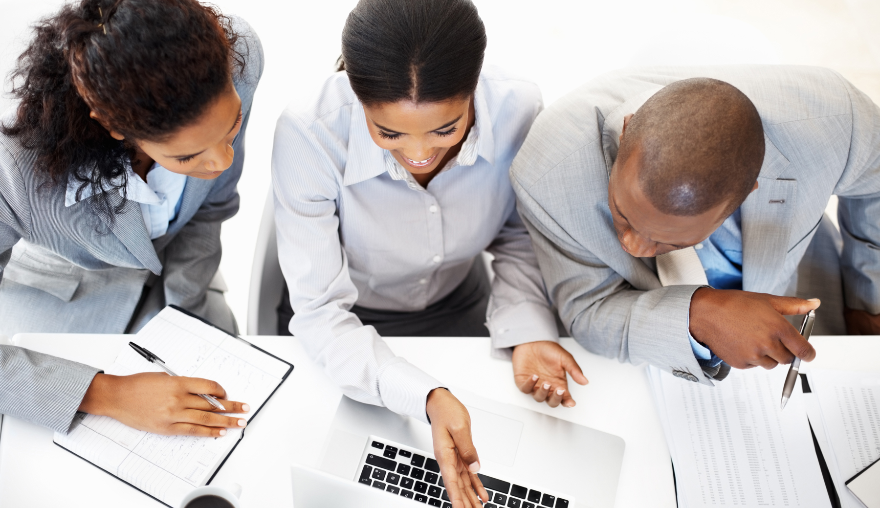 3 IT Consultants working at a desk with a laptop and paperwork