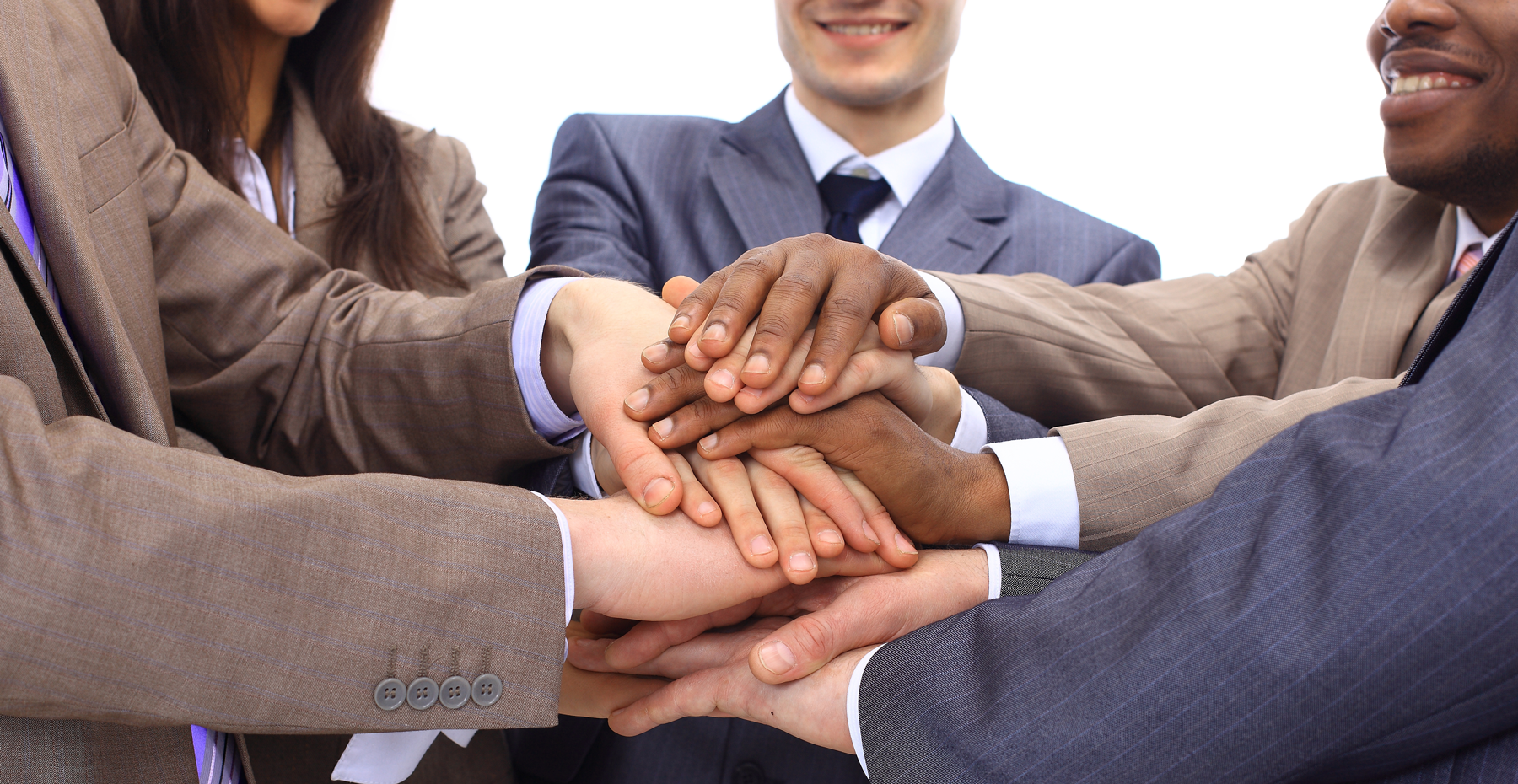 group of business professionals stacking hands while deciding the main reasons to outsource technology in America